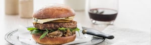 Burger with Angel Bay patty on a plate with cutlery.