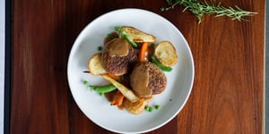 Angel Bay lamb patties on a plate with roast vegetables and gravy.