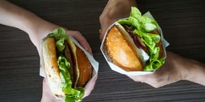 Two Angel Bay beef burgers being held.