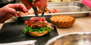 Burger being created with Angel Bay beef patty, lettice, cheese, tomato and bacon.