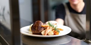 Chef serving up roast meal with Angel Bay lamb rissoles covered in gravy.